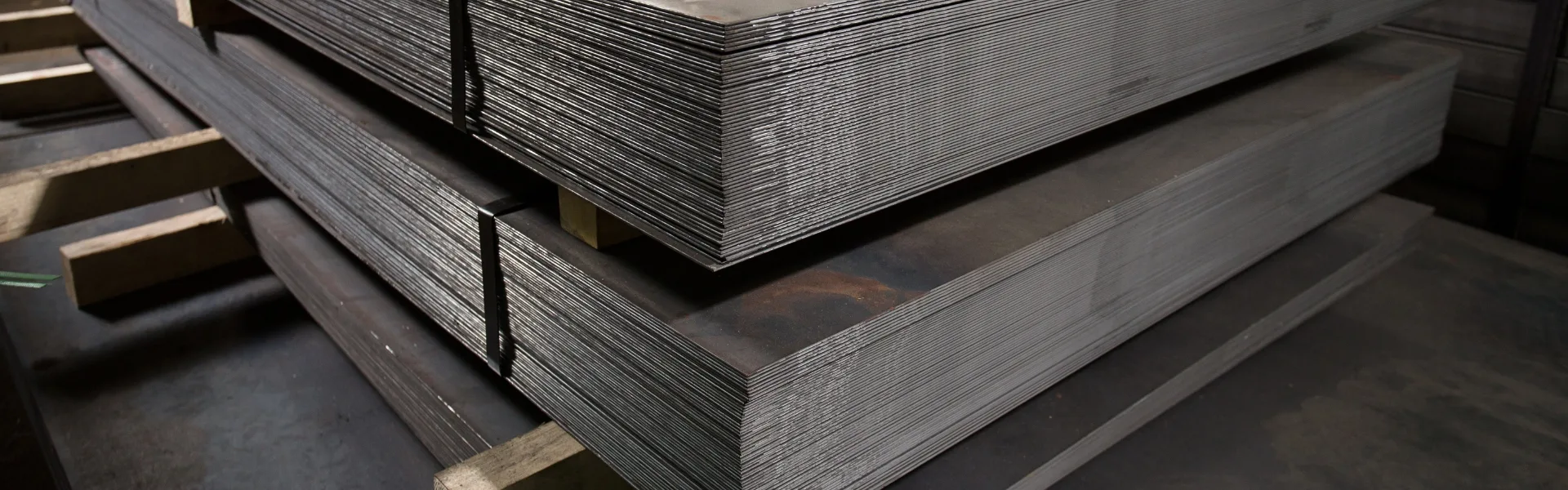 Στοίβες χαλύβδινων φύλλων σε αποθήκη, συμβολίζοντας τη βιομηχανική δυναμικότητα και την εφοδιαστική υποδομή της Axinar – επικοινωνήστε μαζί μας
