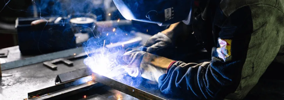Professional welder performing MIG or TIG welding on a metal frame at Axinar’s fabrication facility. Bright arc and protective gear visible.